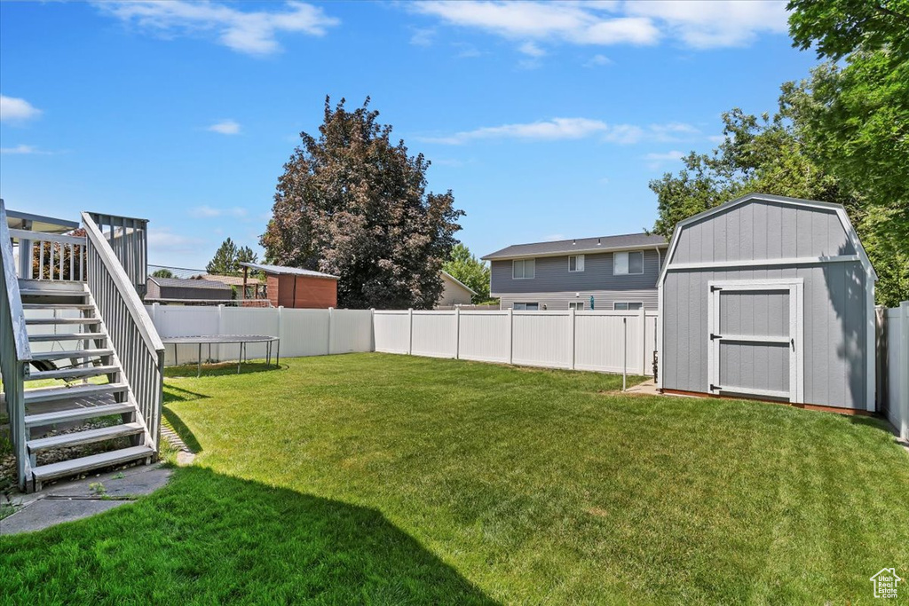 Fenced backyard featuring a storage unit and stairway