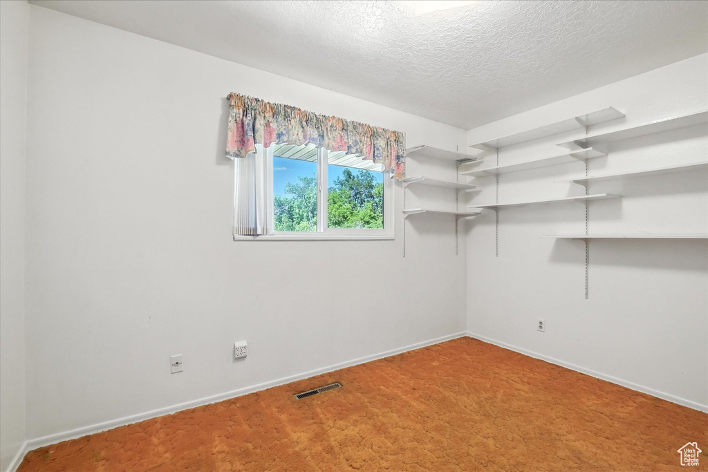 Carpeted empty room with baseboards and a textured ceiling