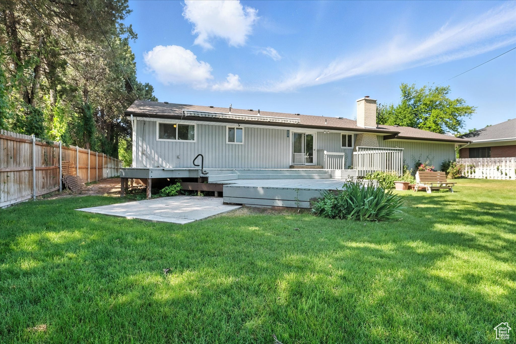 Rear view of house featuring a patio area, a deck, and a chimney