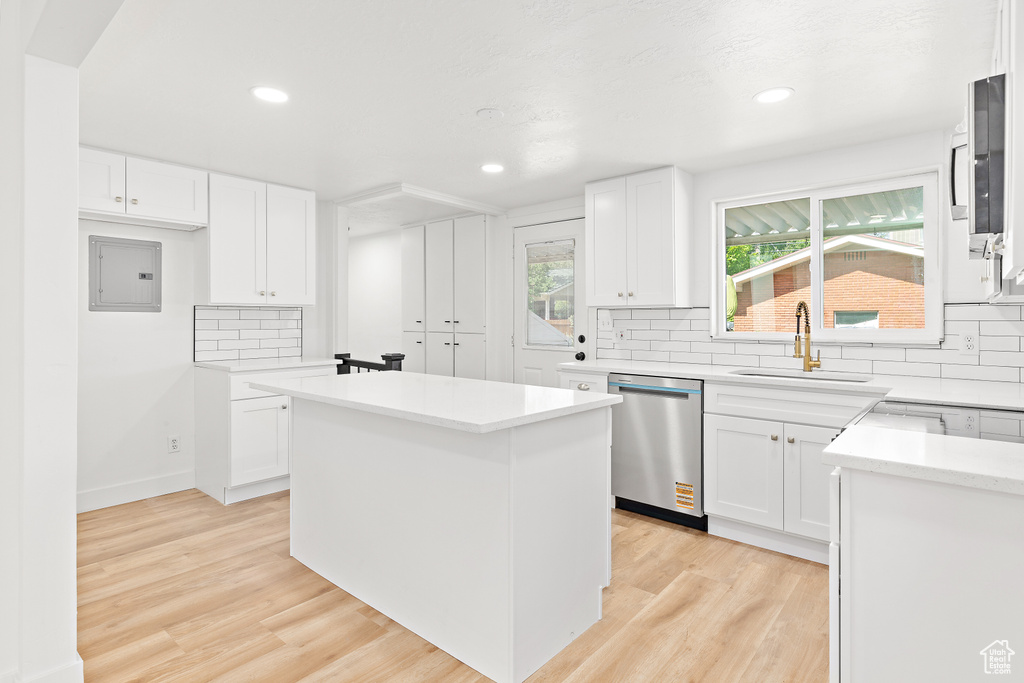 Kitchen featuring stainless steel dishwasher, electric panel, backsplash, a kitchen island, and recessed lighting