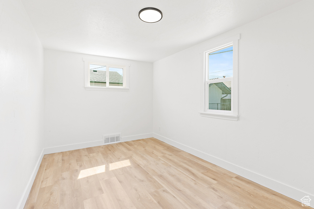 Unfurnished room featuring healthy amount of natural light and wood finished floors