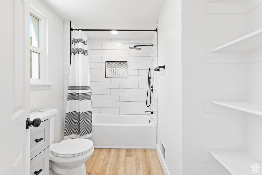 Bathroom with wood finished floors and shower / bath combo