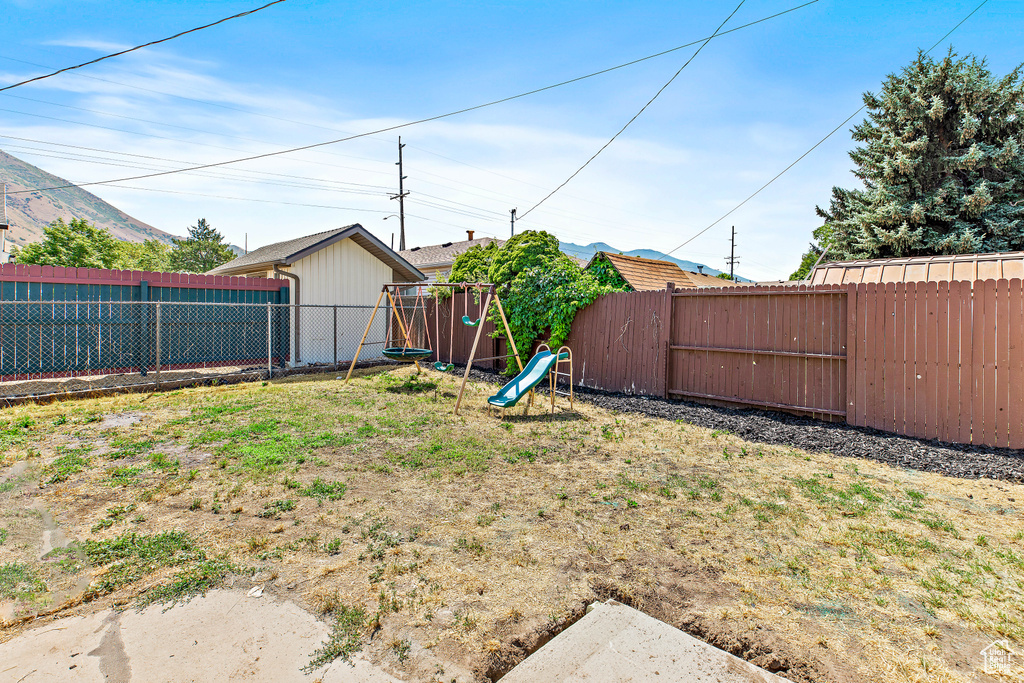 Fenced backyard featuring a playground