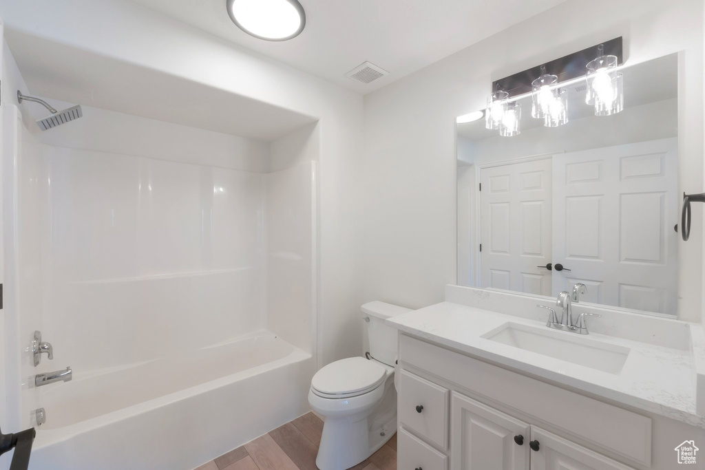 Bathroom featuring wood finished floors, vanity, and shower / tub combination