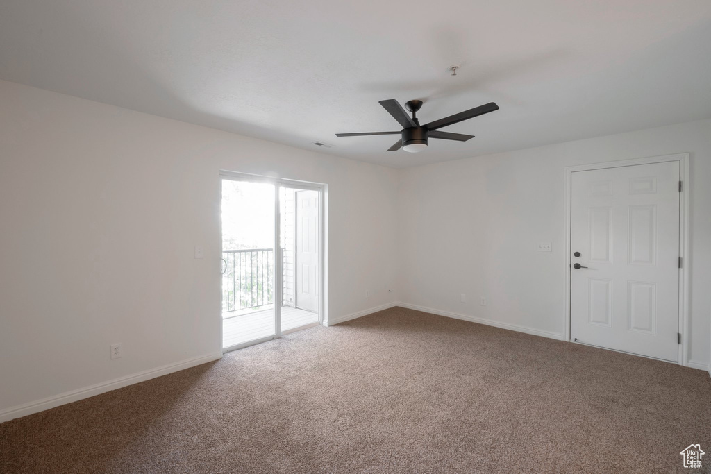 Carpeted spare room featuring ceiling fan and baseboards