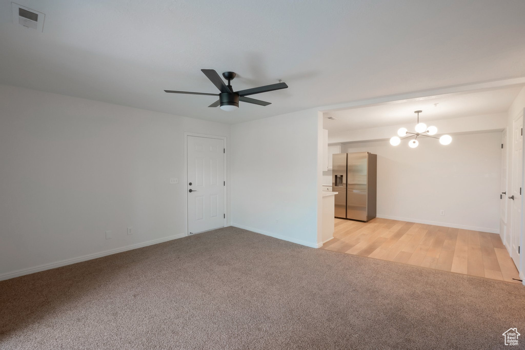 Unfurnished room featuring light colored carpet, a chandelier, and ceiling fan