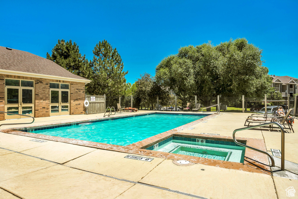 Community pool with a community hot tub, a patio, and view of wooded area