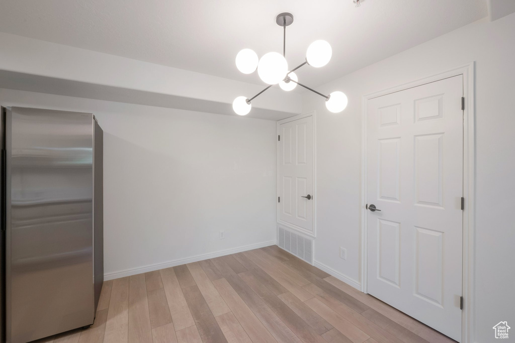 Unfurnished dining area with light wood-style flooring and a chandelier