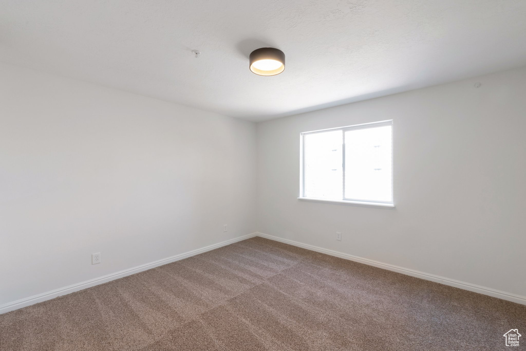 Unfurnished room featuring carpet flooring and fire sprinkler in ceiling
