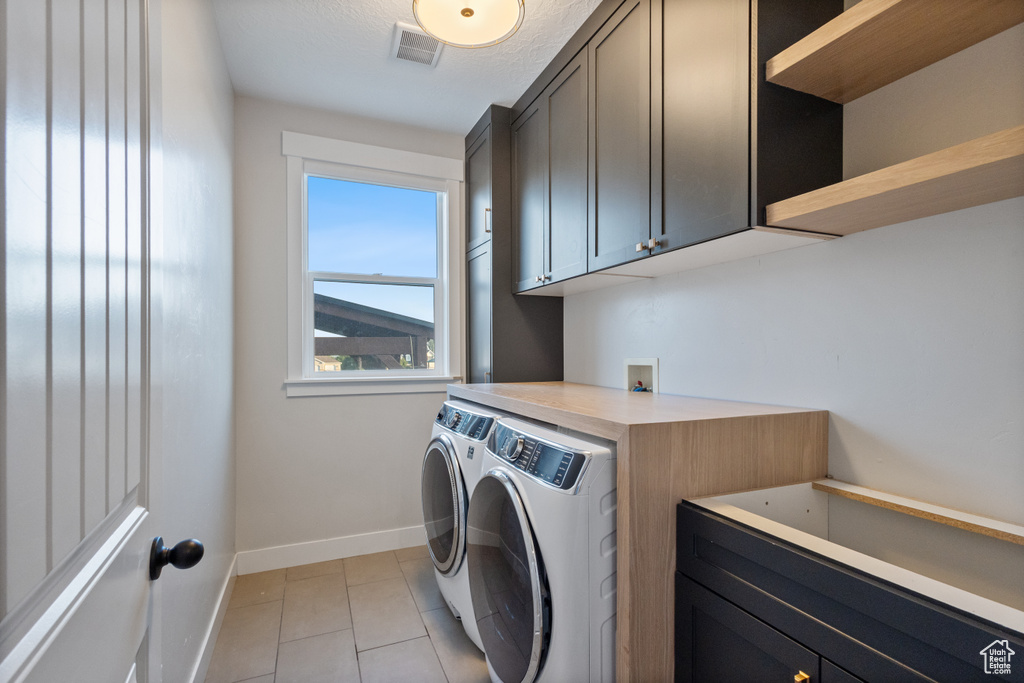 Laundry room with separate washer and dryer, cabinet space, and light tile patterned flooring