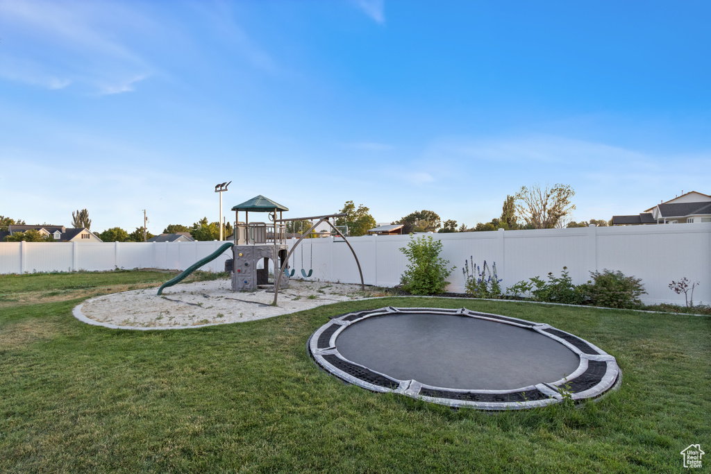 Fenced backyard with a trampoline and a playground