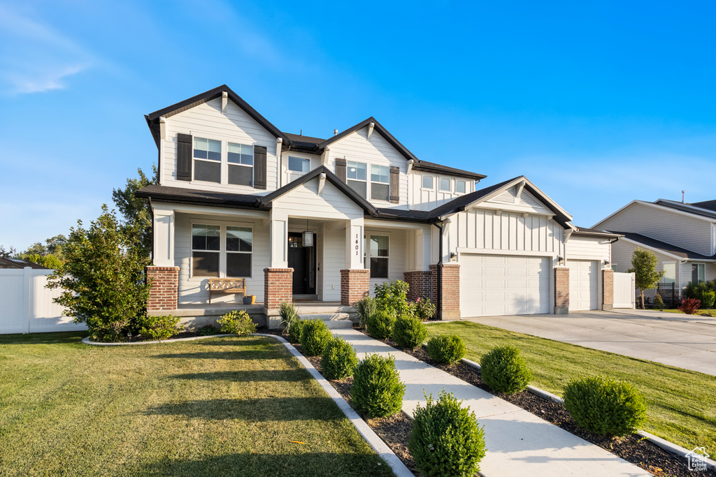 Craftsman inspired home with board and batten siding, brick siding, a garage, covered porch, and driveway