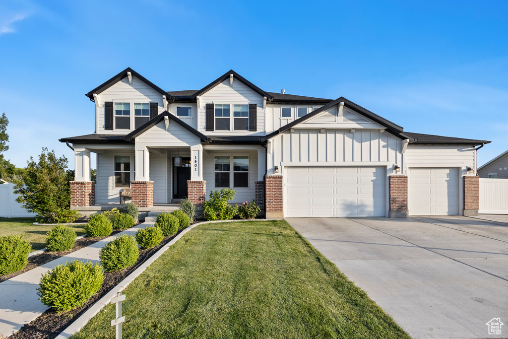 View of front facade featuring an attached garage, concrete driveway, brick siding, and board and batten siding