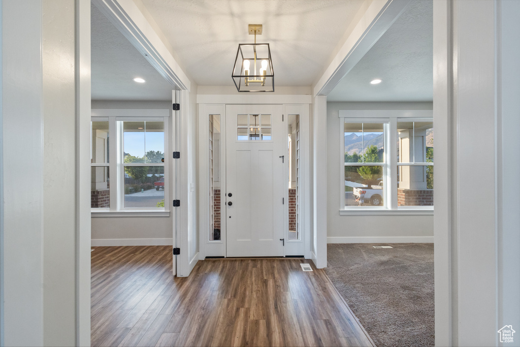 Entryway with healthy amount of natural light, wood finished floors, a chandelier, and recessed lighting
