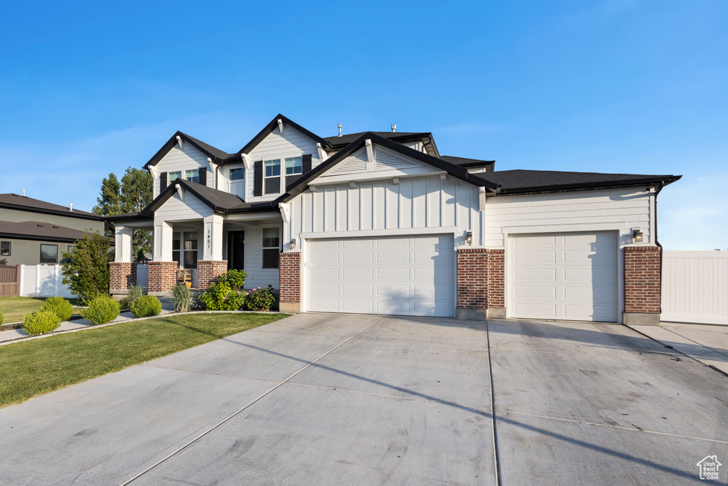 View of front of property with a garage, brick siding, concrete driveway, board and batten siding, and a front yard
