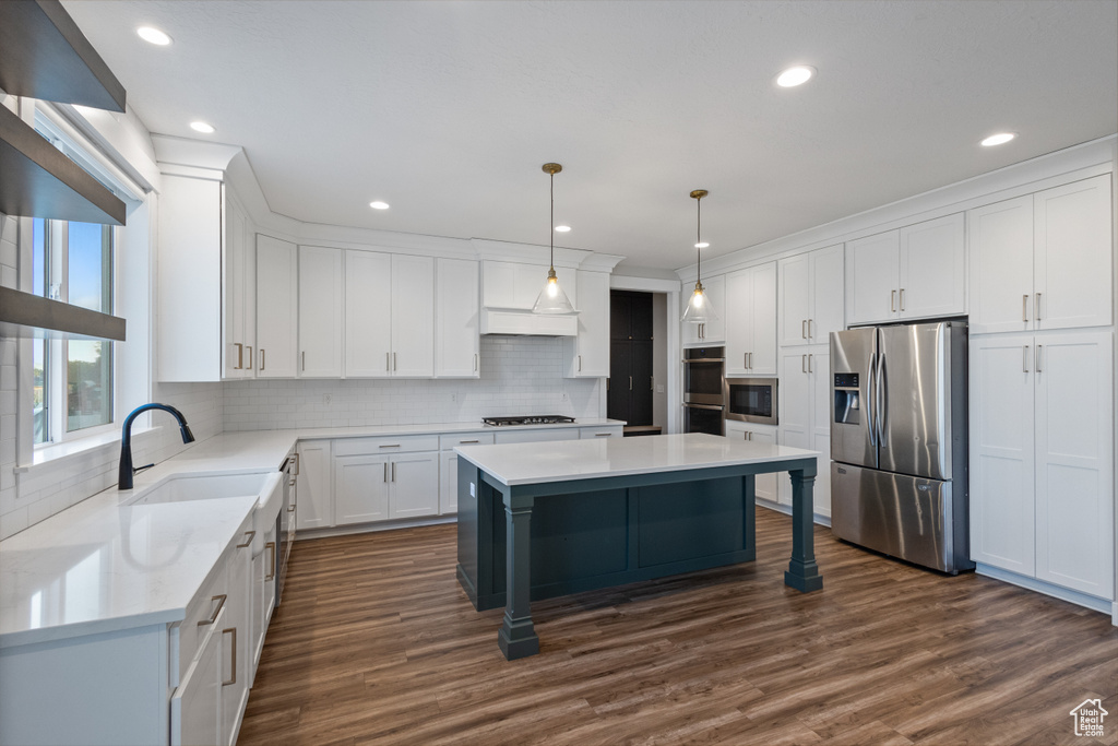 Kitchen featuring stainless steel appliances, tasteful backsplash, a center island, dark wood finished floors, and recessed lighting