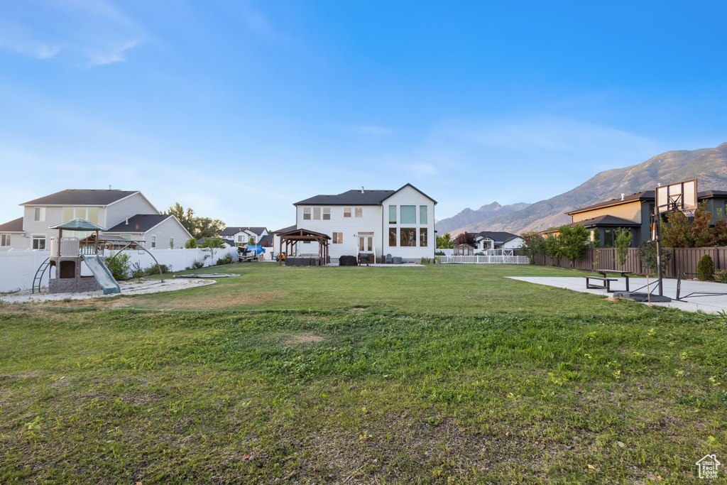 Fenced backyard featuring a gazebo, a mountain view, and a patio