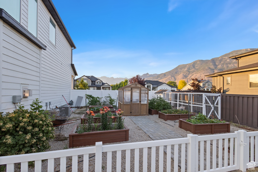 Fenced backyard with a vegetable garden, a storage shed, a mountain view, and a residential view