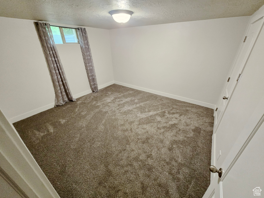 Unfurnished room featuring a textured ceiling and carpet flooring