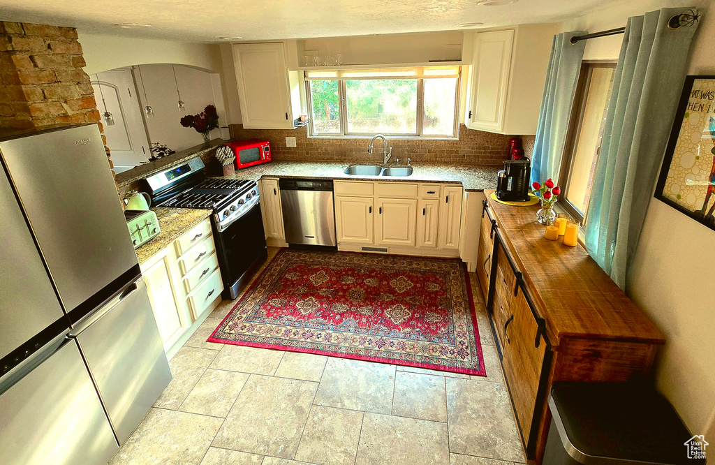 Kitchen featuring appliances with stainless steel finishes, tasteful backsplash, and light stone finish flooring