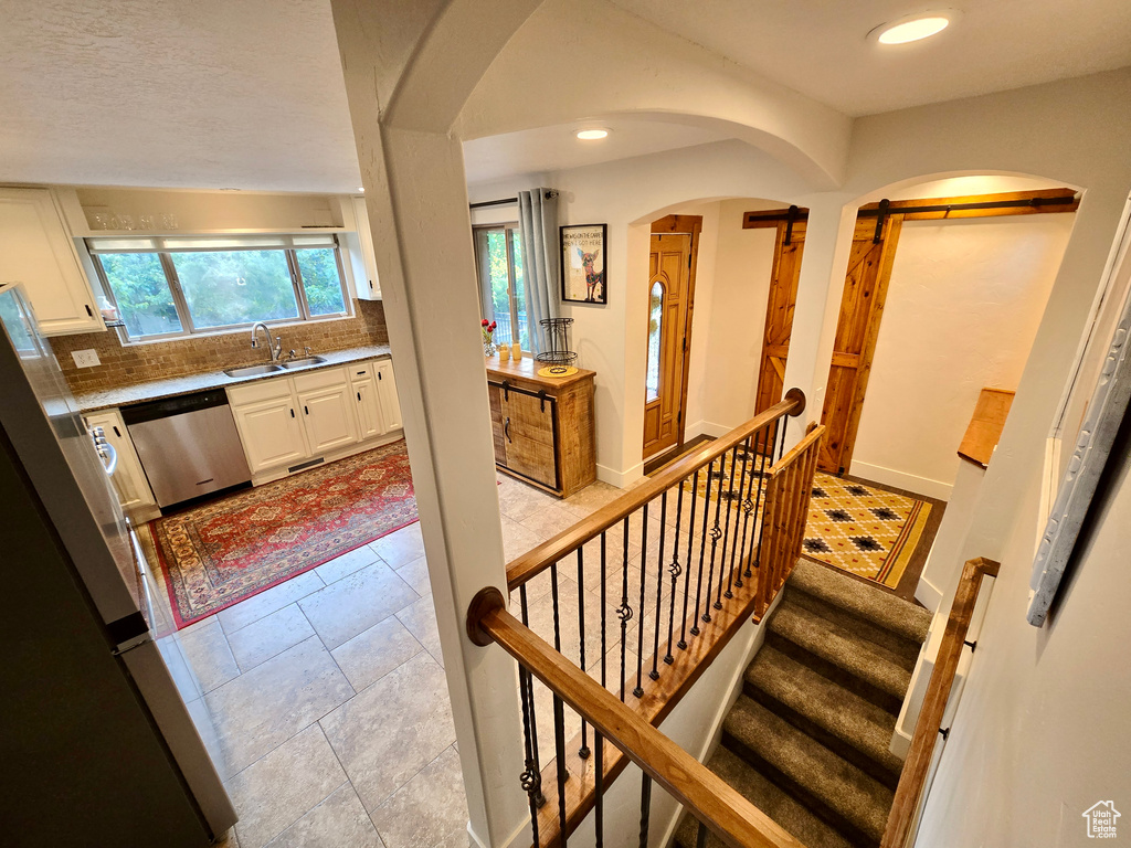 Foyer entrance with arched walkways, recessed lighting, and stairs