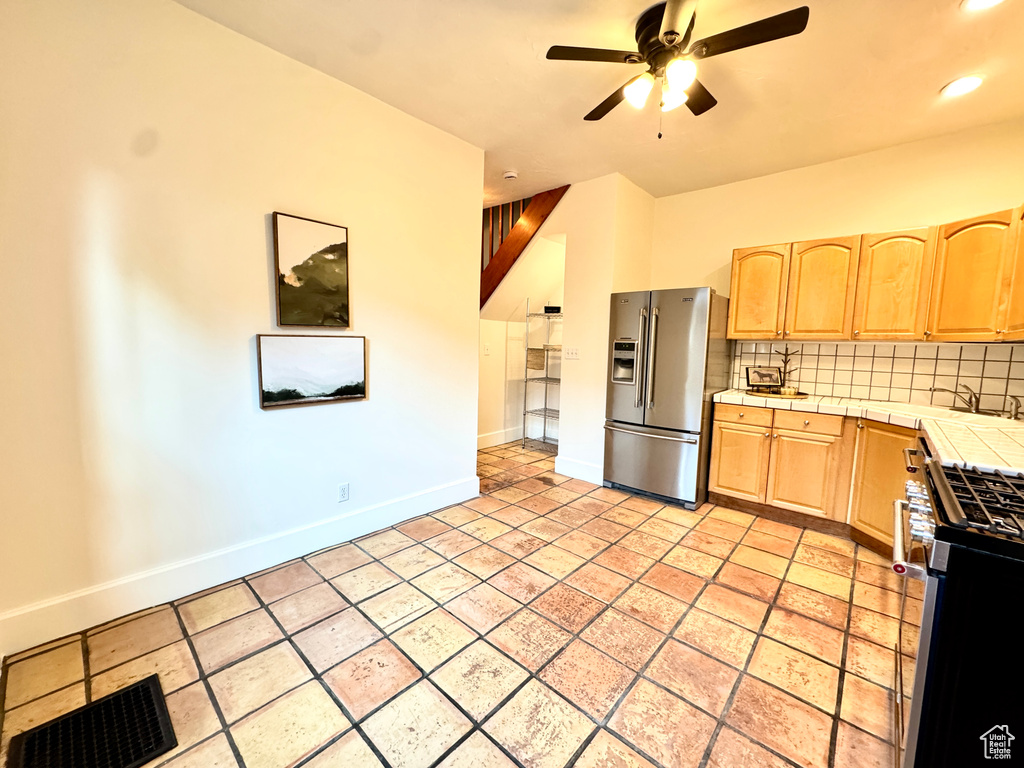Kitchen with appliances with stainless steel finishes, tile counters, light brown cabinetry, a ceiling fan, and recessed lighting