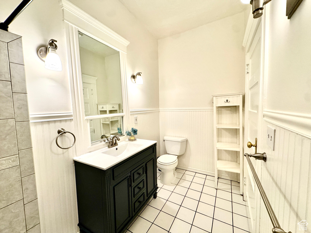 Bathroom with a wainscoted wall, vanity, and tile patterned flooring