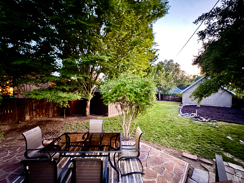 Fenced backyard featuring a patio area and an outbuilding