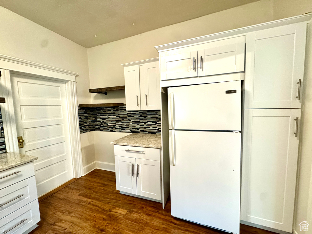 Kitchen with freestanding refrigerator, white cabinetry, open shelves, tasteful backsplash, and dark wood-style flooring