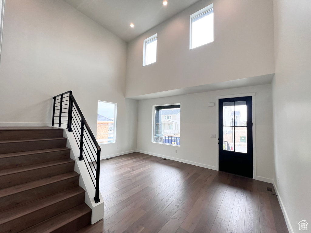 Foyer with stairs, a towering ceiling, dark wood-style flooring, and recessed lighting