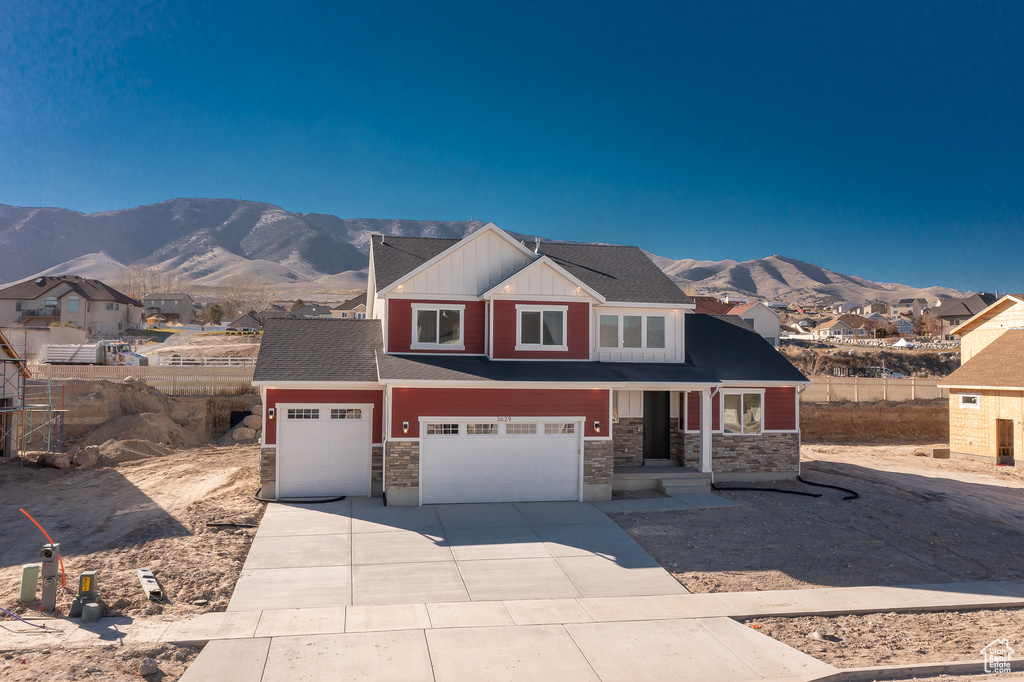 Craftsman-style house featuring a mountain view, board and batten siding, stone siding, and driveway