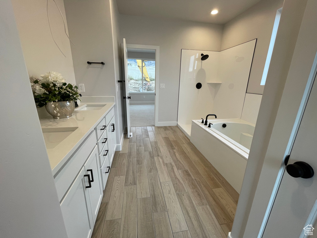 Full bathroom with double vanity, wood finished floors, shower / tub combination, and recessed lighting