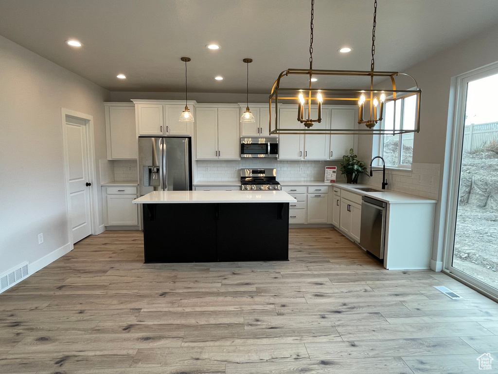 Kitchen featuring appliances with stainless steel finishes, recessed lighting, light countertops, backsplash, and a center island
