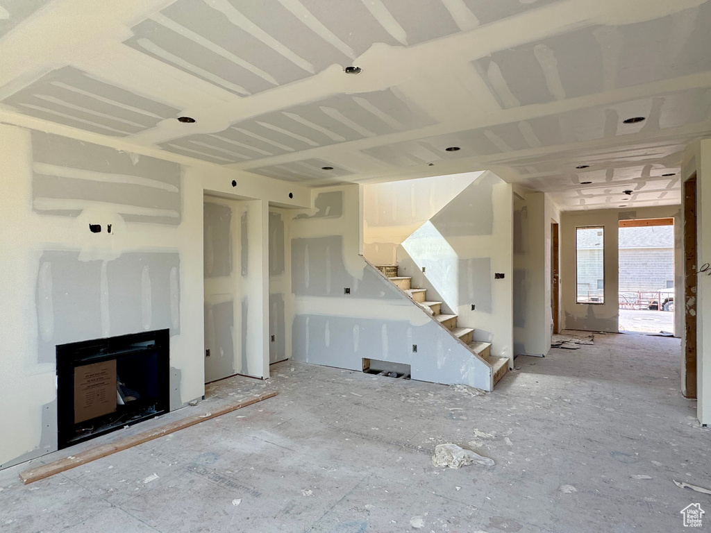 Unfurnished living room featuring stairway and a fireplace