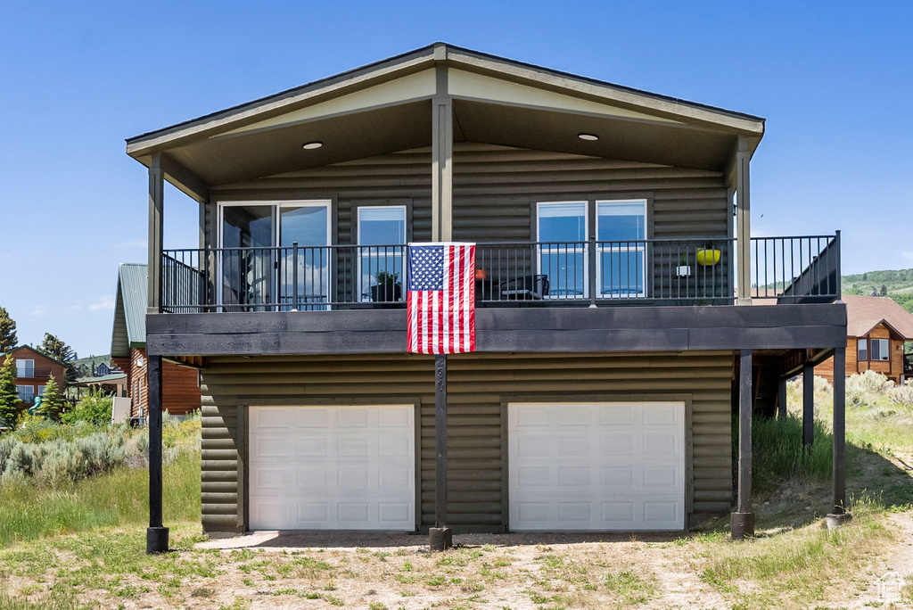 Rear view of property with an attached garage, driveway, and log veneer siding