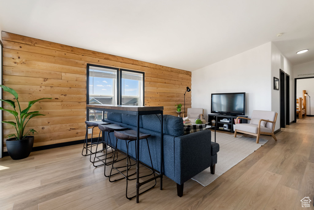 Living area with light wood finished floors and wood walls
