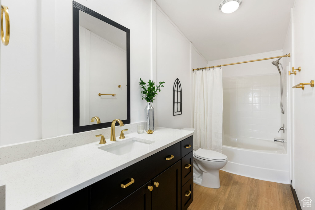 Bathroom featuring wood finished floors, vanity, and shower / tub combo