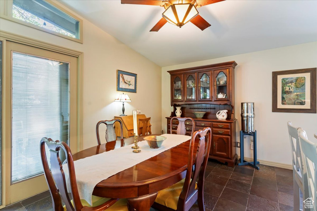 Dining area with vaulted ceiling, a ceiling fan, and dark stone finish flooring