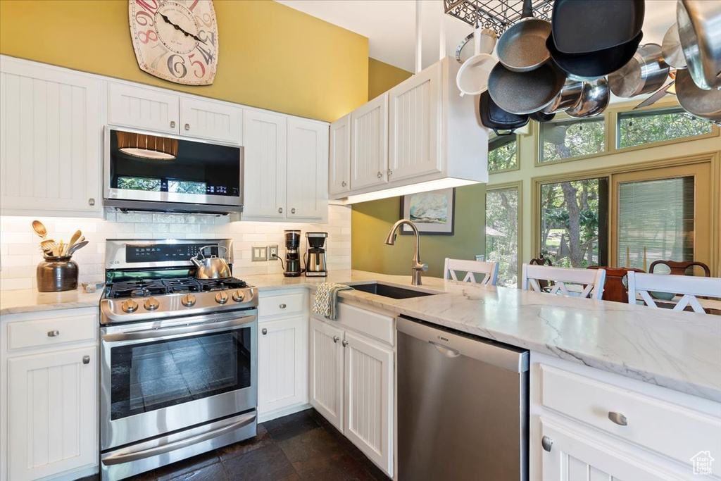 Kitchen with stainless steel appliances, tasteful backsplash, and white cabinetry