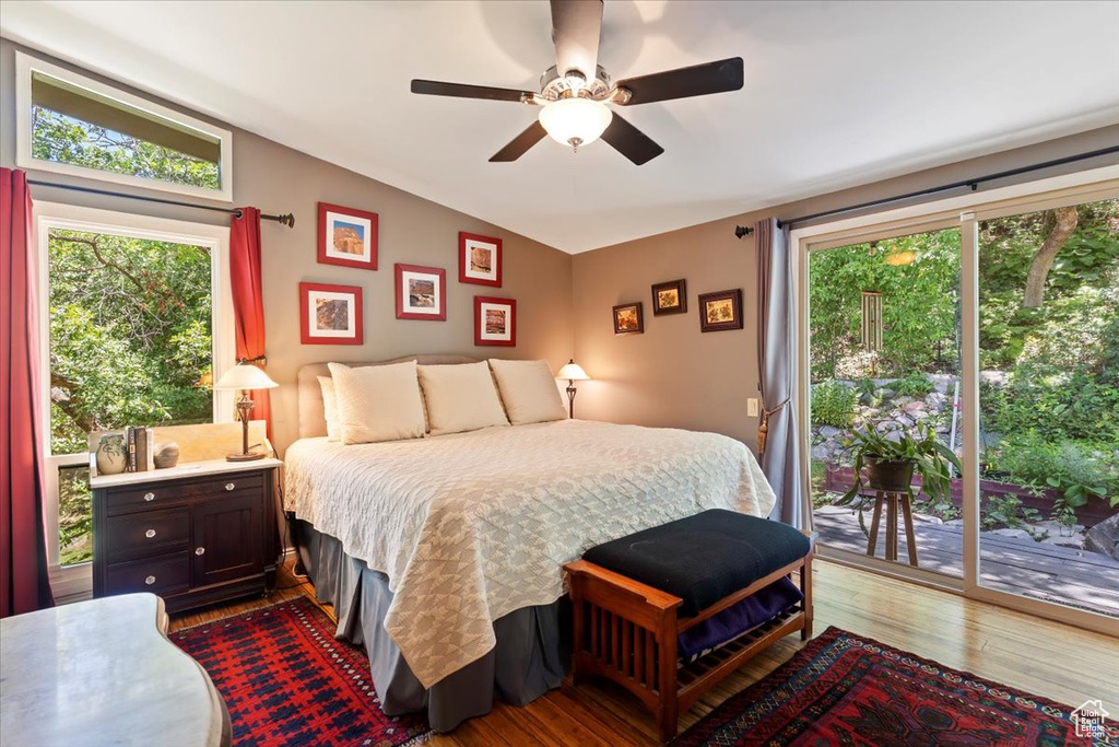 Bedroom with access to exterior, vaulted ceiling, multiple windows, and dark wood-type flooring