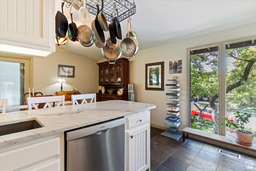Kitchen featuring dishwasher, stone tile flooring, white cabinets, light stone countertops, and lofted ceiling