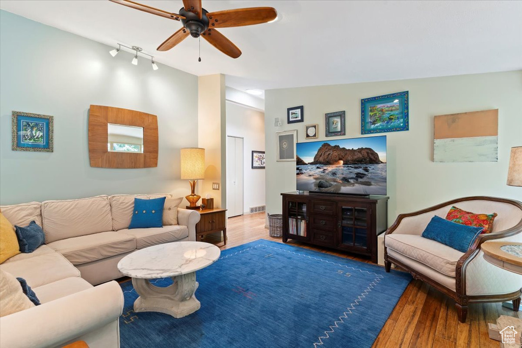 Living room with ceiling fan, lofted ceiling, wood finished floors, and rail lighting