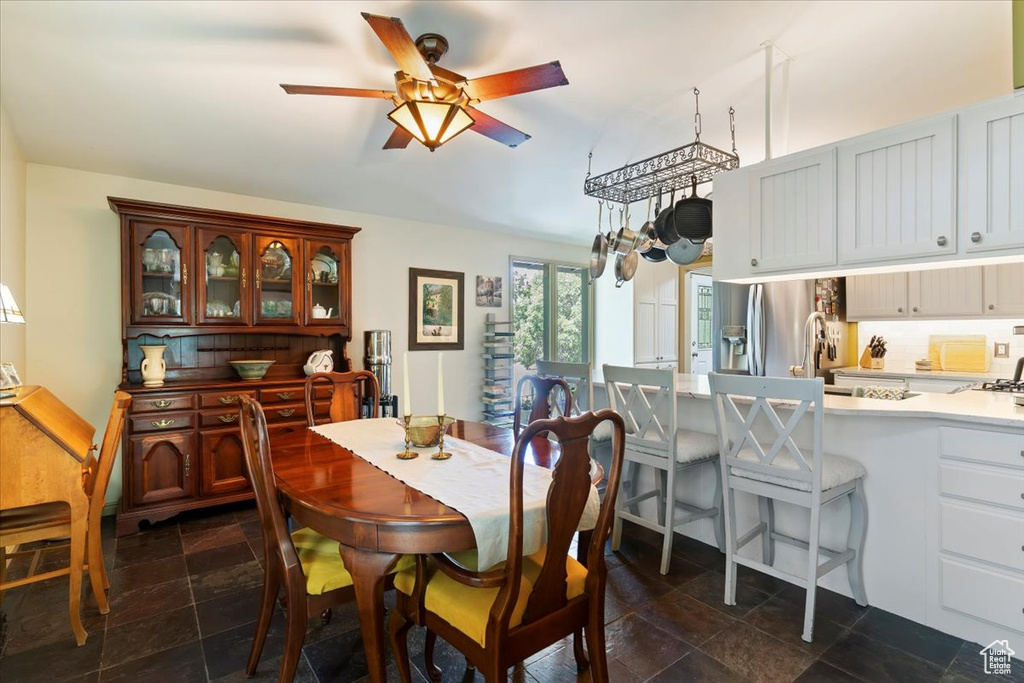 Dining space featuring a ceiling fan and dark stone finish floors