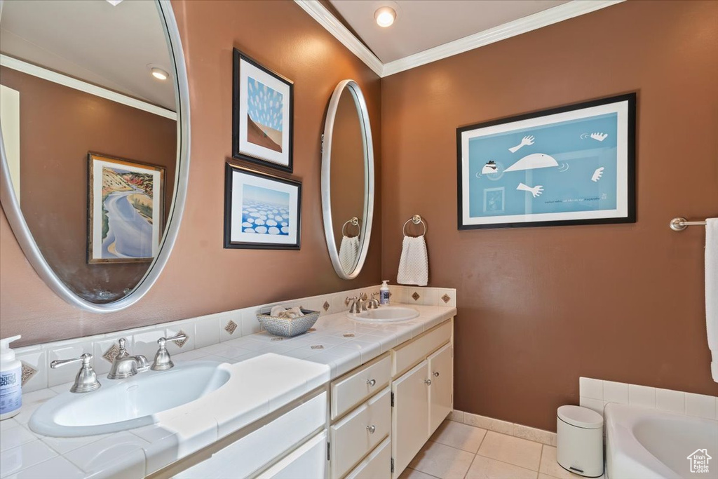 Bathroom with double vanity, tile patterned floors, a bath, and crown molding