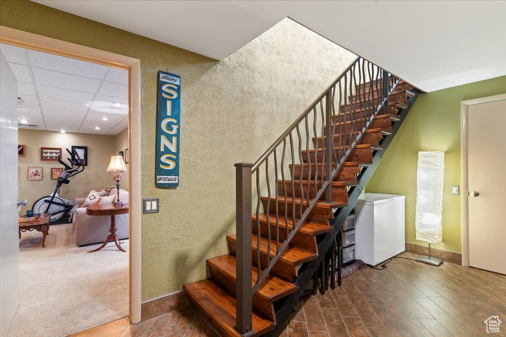Staircase featuring wood finished floors and a textured wall
