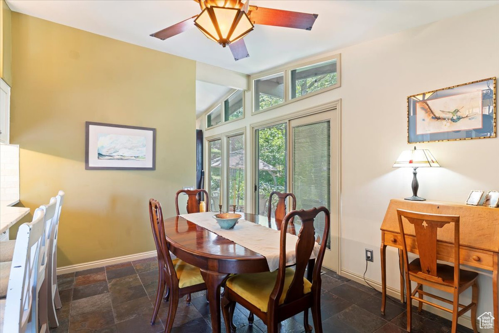 Dining room with stone tile flooring, ceiling fan, and vaulted ceiling