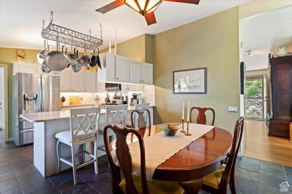 Dining space featuring stone tile floors, a towering ceiling, and a ceiling fan