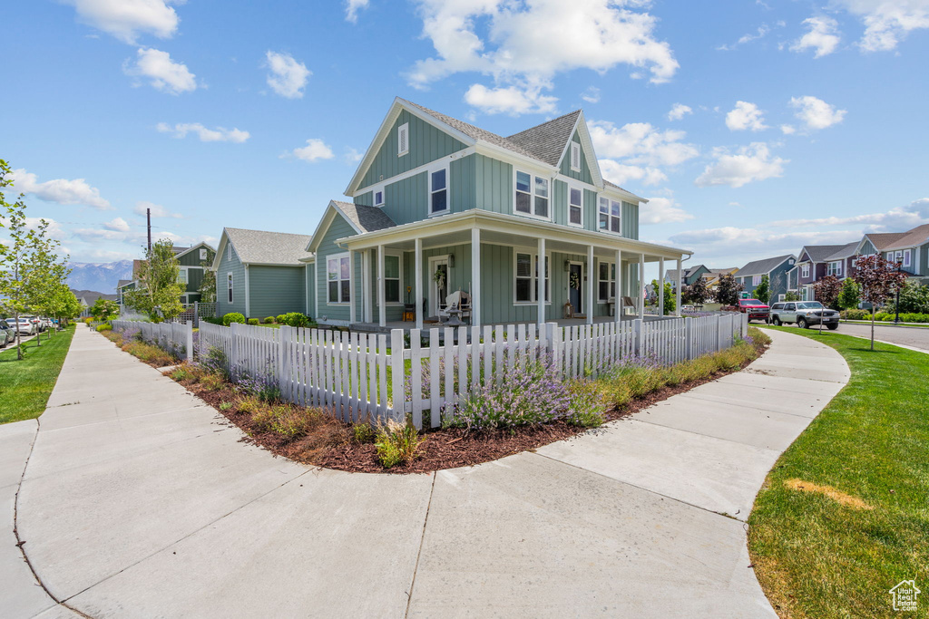 View of front of house with covered porch, a residential view, board and batten siding, a fenced front yard, and a shingled roof