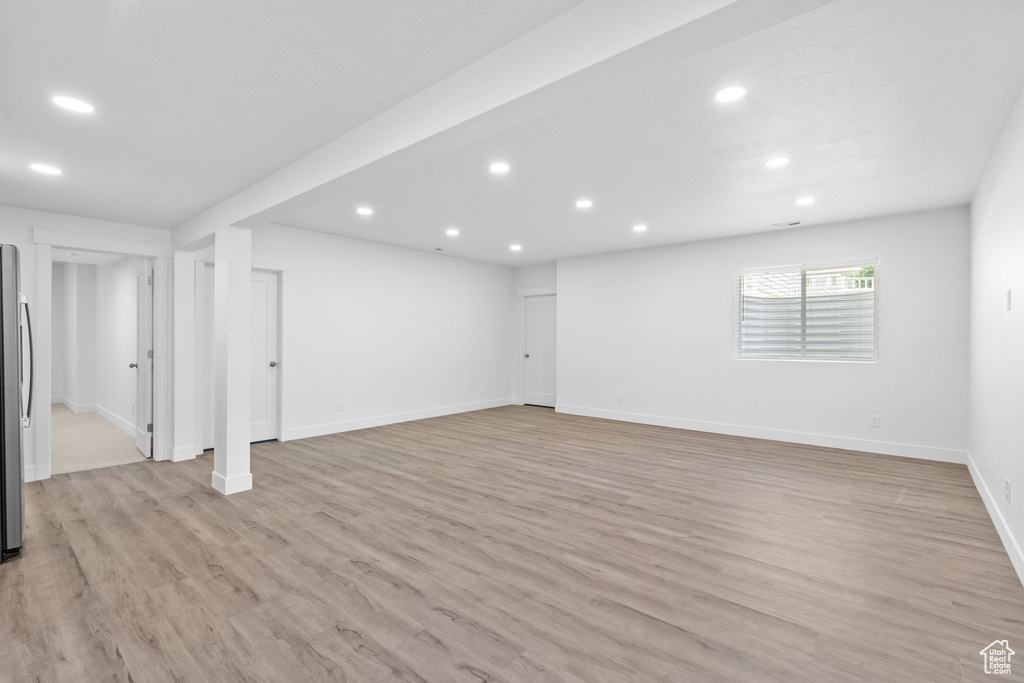 Basement featuring recessed lighting, light wood-style floors, and freestanding refrigerator