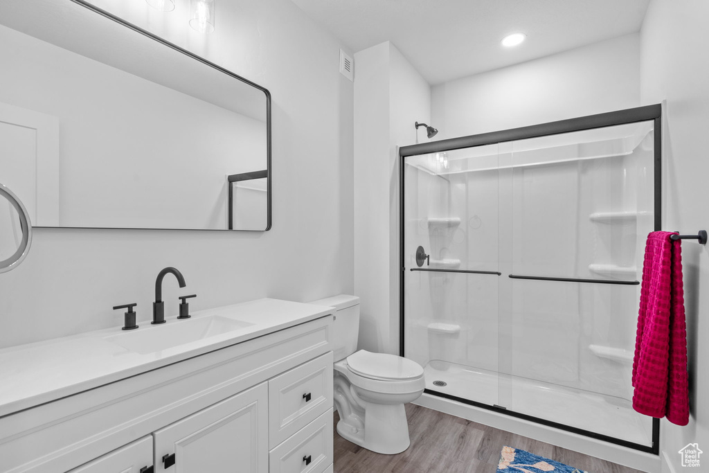 Bathroom with a stall shower, vanity, wood finished floors, and recessed lighting